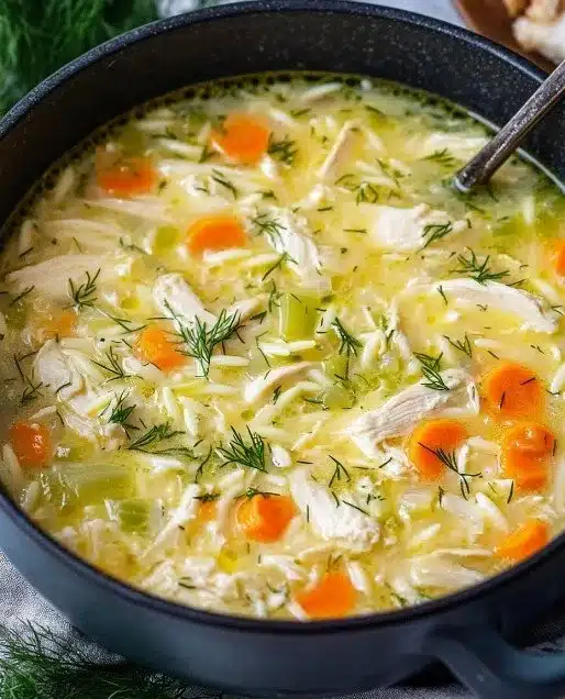 Creamy chicken and orzo soup garnished with fresh dill in a bowl