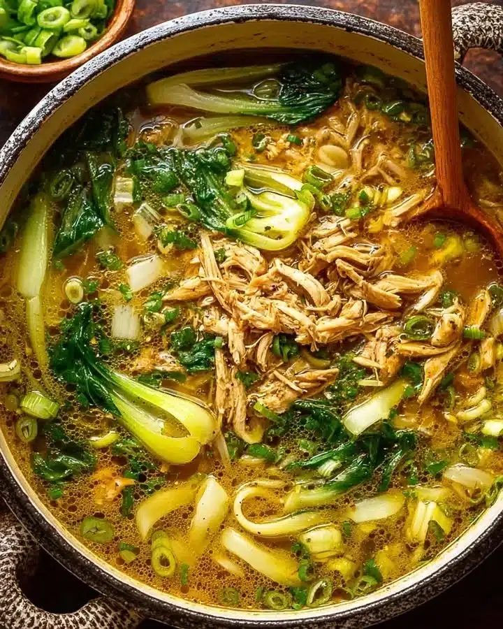Bowl of ginger chicken and rice soup with bok choy, fresh ingredients, comforting dish.