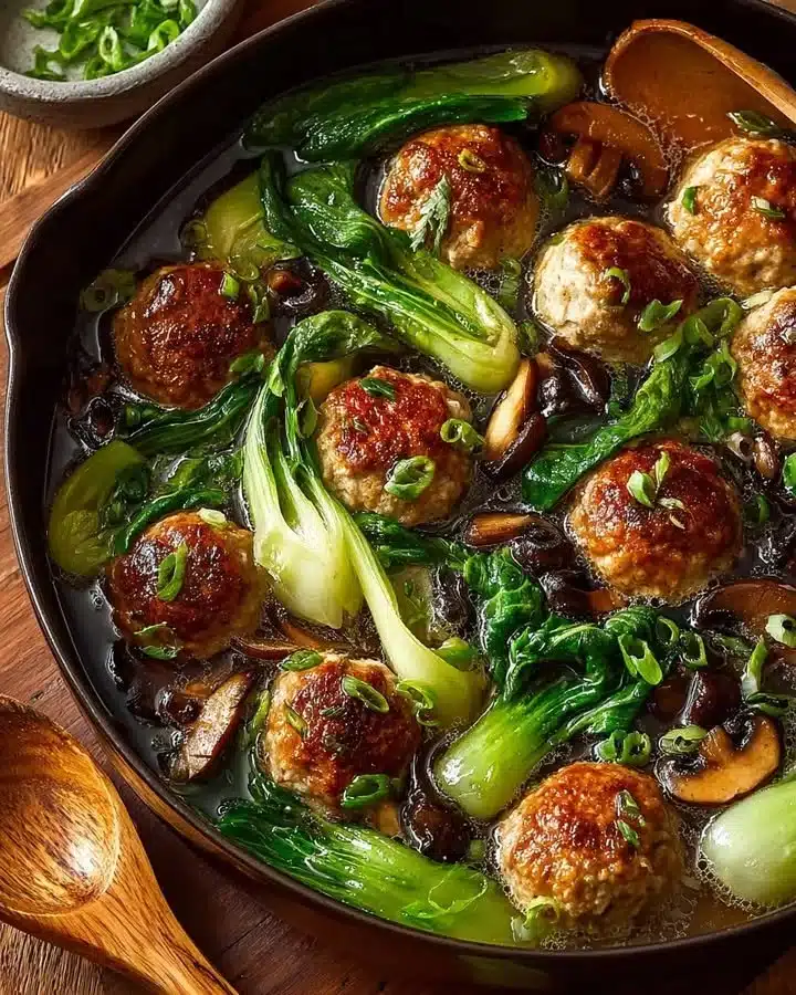 Steamed Chicken Meatballs with Bok Choy and Shiitake Mushrooms 1 Steamed chicken meatballs with bok choy and shiitake mushrooms on a plate.